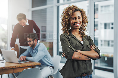 Buy stock photo Portrait of a confident young woman with her colleagues in the background at work