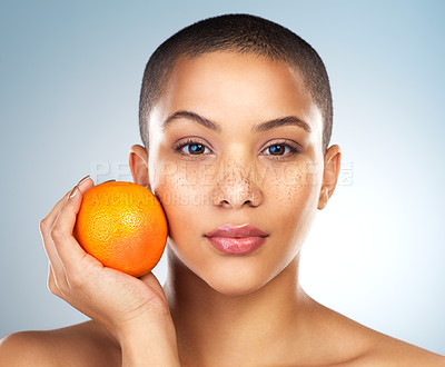 Buy stock photo Studio shot of a beautiful young woman posing with an orange against a blue background