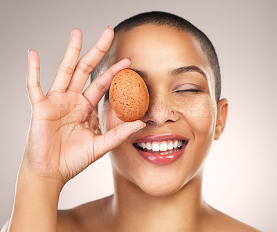 Buy stock photo Studio shot of a beautiful young woman holding a egg against her face