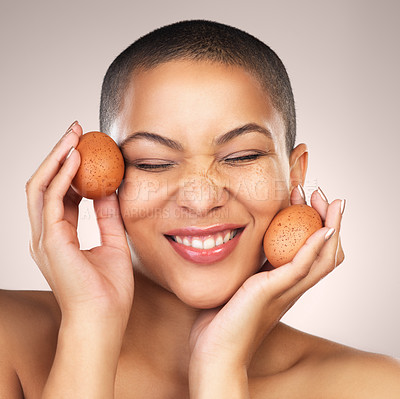 Buy stock photo Studio shot of a beautiful young woman holding eggs against her face