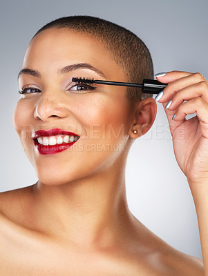 Buy stock photo Studio shot of a beautiful young woman applying mascara against a grey background