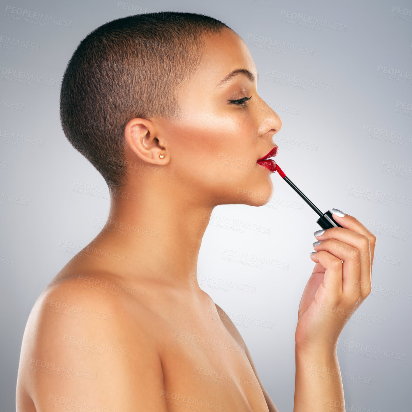 Buy stock photo Studio shot of a beautiful young woman applying red lipstick against a grey background