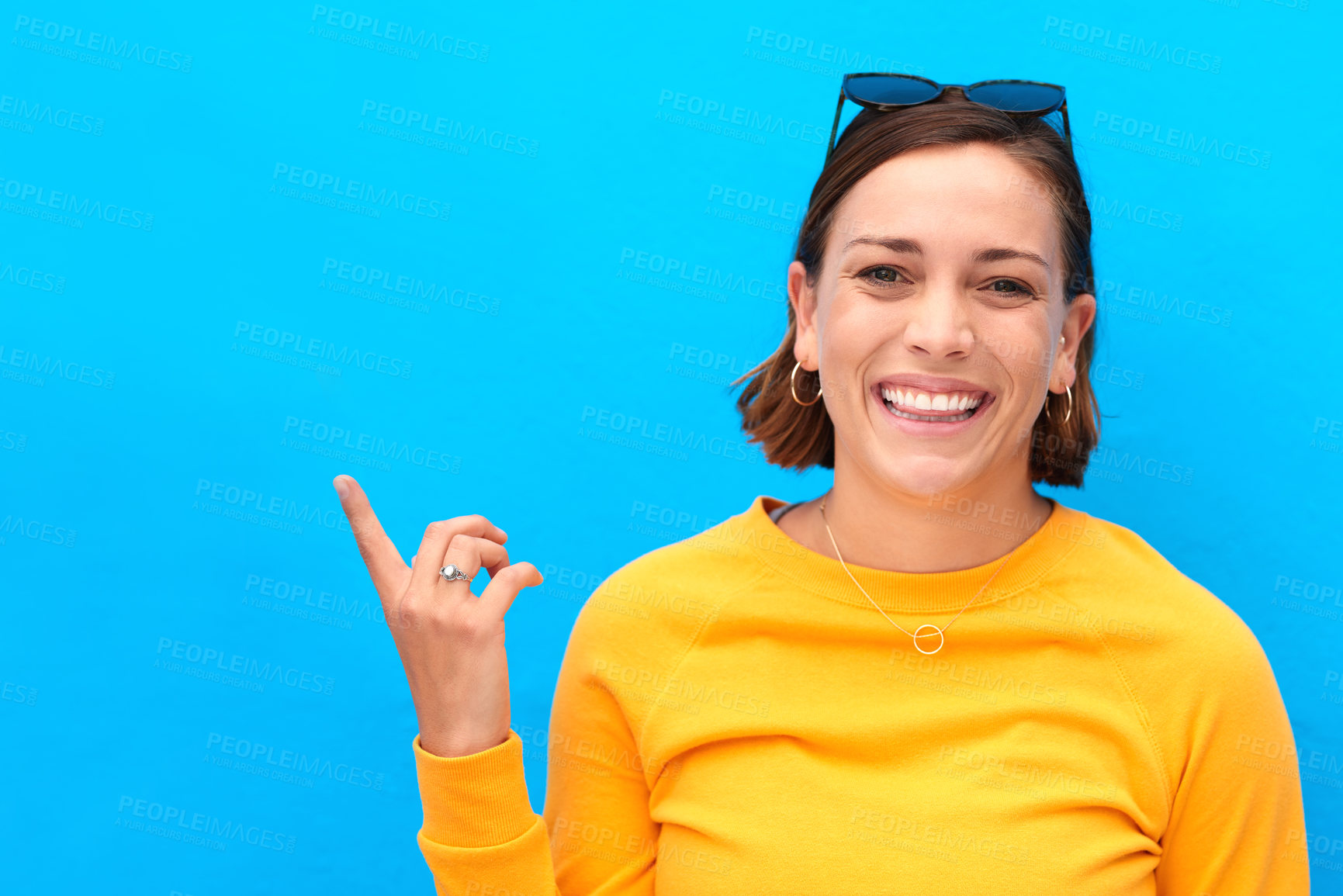 Buy stock photo Portrait, woman and pointing for direction in studio with deal choice, announcement and sunglasses giveaway. Smile, girl and show steps with application news, advertising product and blue background