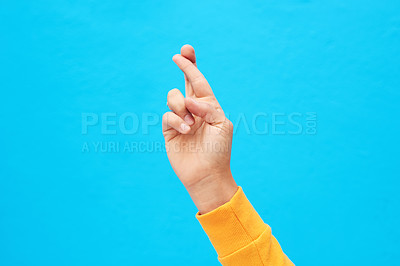 Buy stock photo Cropped shot of an unrecognizable hand crossing fingers against a blue background