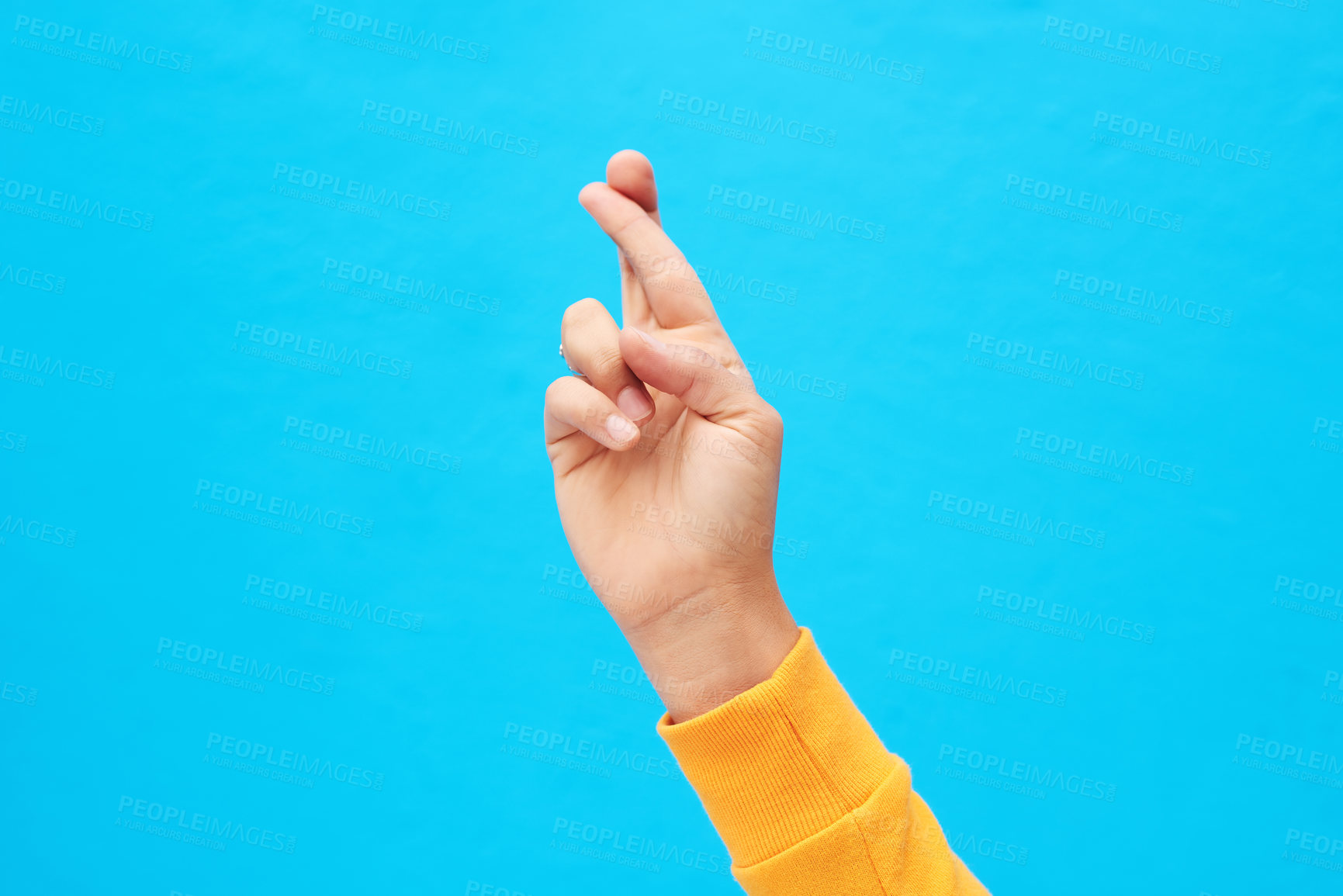 Buy stock photo Cropped shot of an unrecognizable hand crossing fingers against a blue background