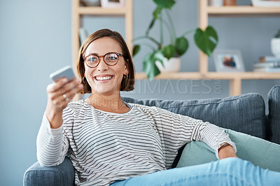 Buy stock photo Cropped shot of a happy young woman using the remote control on the sofa at home