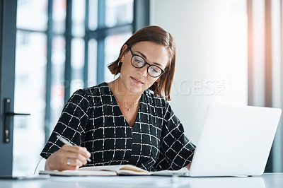 Buy stock photo Cropped shot of a focused young businesswoman writing on a notebook in an office