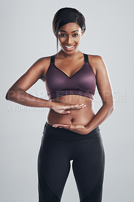 Buy stock photo Studio portrait of an attractive and fit young woman framing her stomach with her hands against a grey background