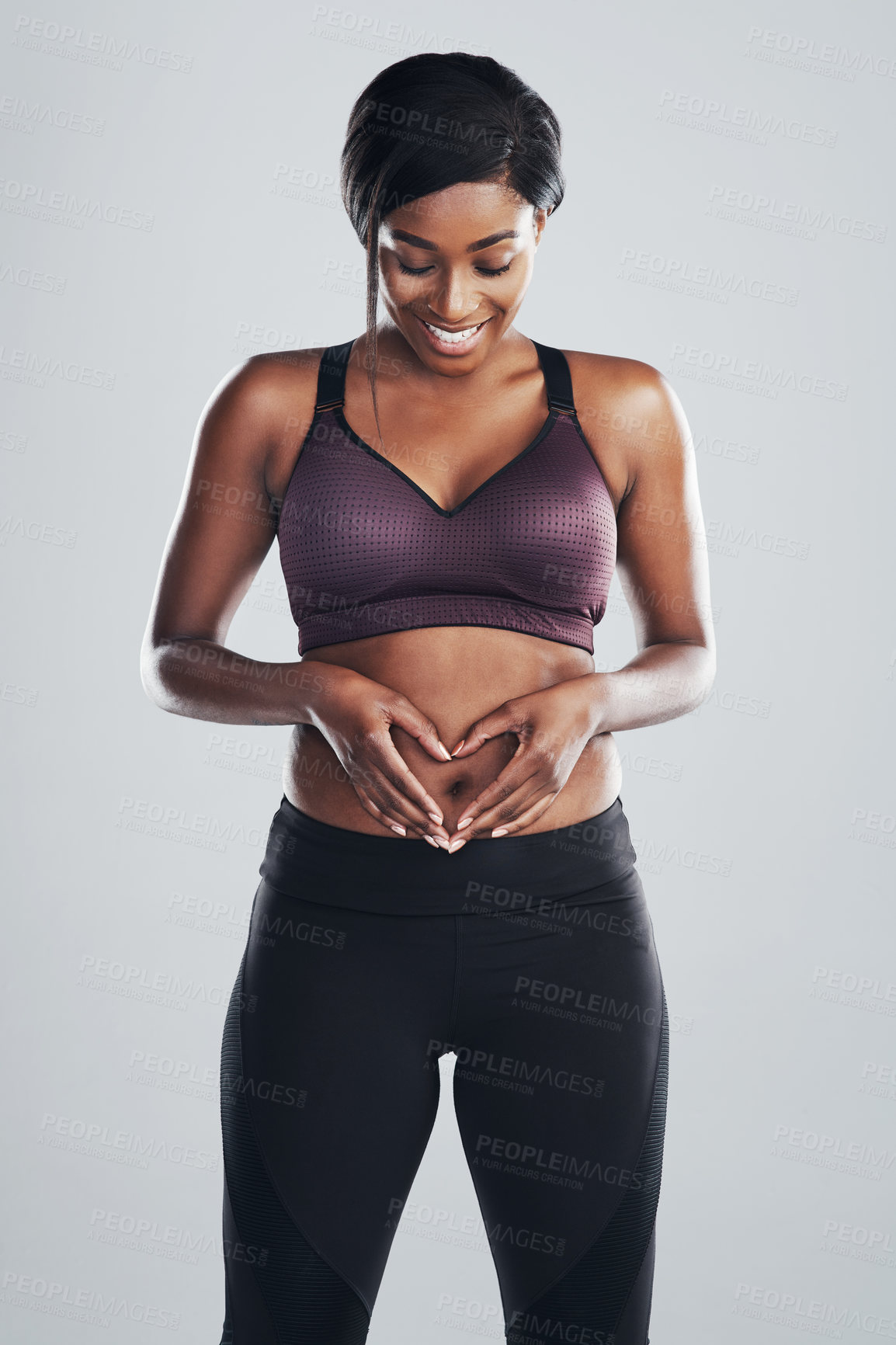 Buy stock photo Studio portrait of an attractive and fit young woman framing her stomach with her hands against a grey background