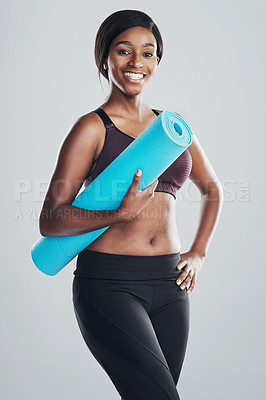 Buy stock photo Studio portrait of an attractive and fit young woman holding an exercise mat against a grey background