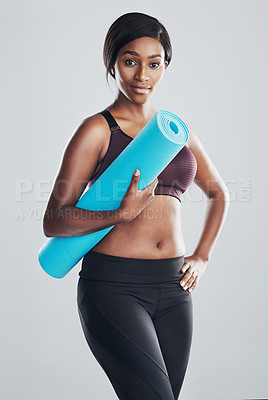 Buy stock photo Studio portrait of an attractive and fit young woman holding an exercise mat against a grey background
