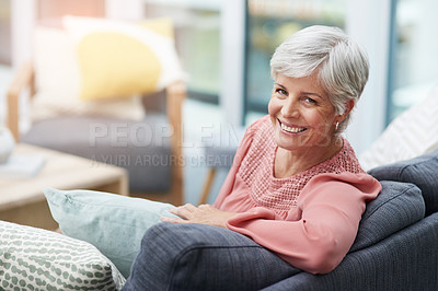 Buy stock photo Shot of a cheerful mature woman relaxing on a sofa at home