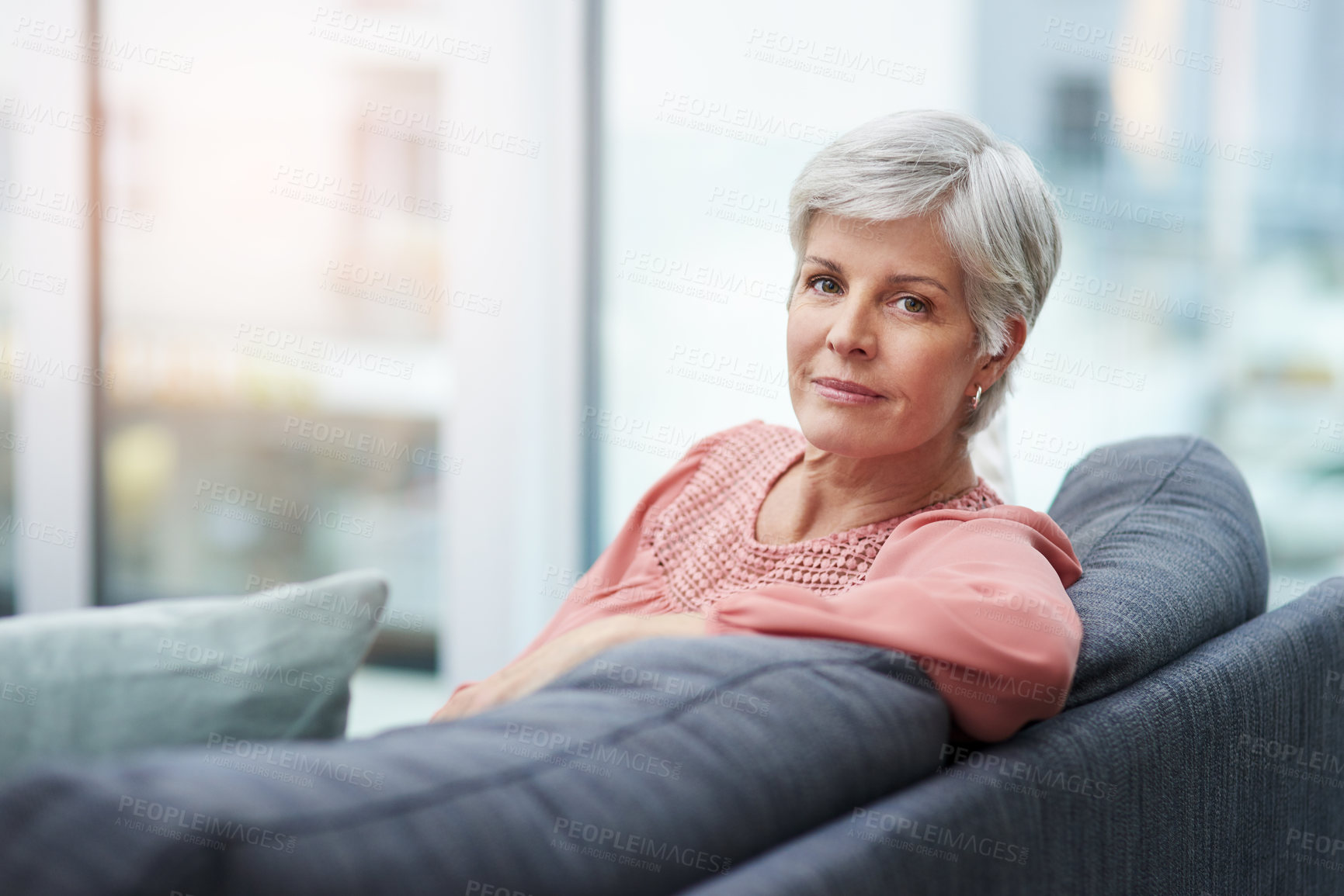 Buy stock photo Portrait of a cheerful mature woman relaxing on her sofa at home