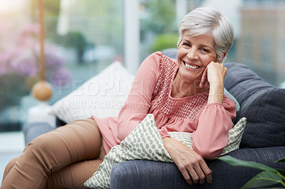 Buy stock photo Portrait of a cheerful mature woman posing with her hand on her chin while relaxing on a sofa at home