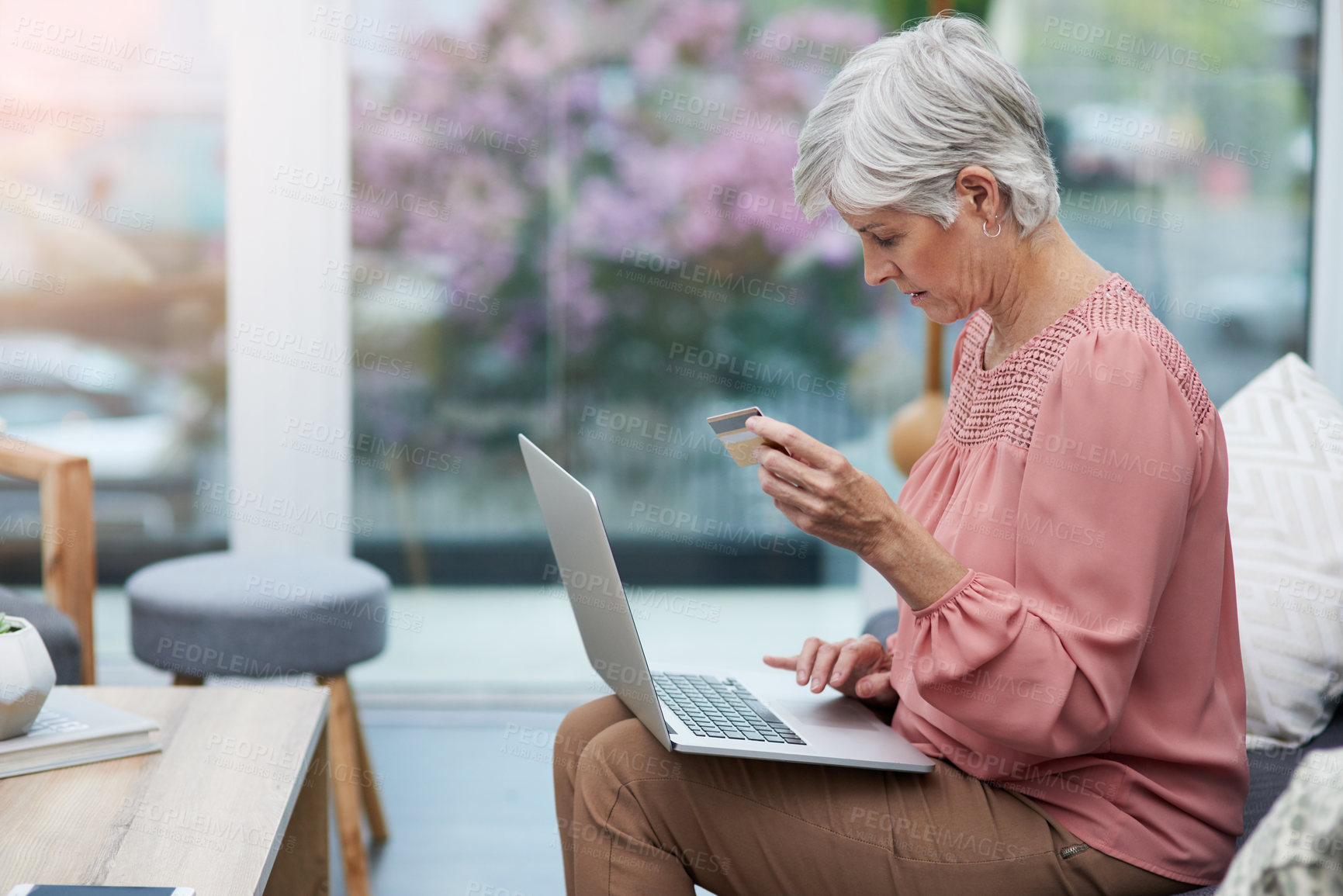 Buy stock photo Shot of a mature woman sitting on a couch and using her laptop to do some online shopping at home
