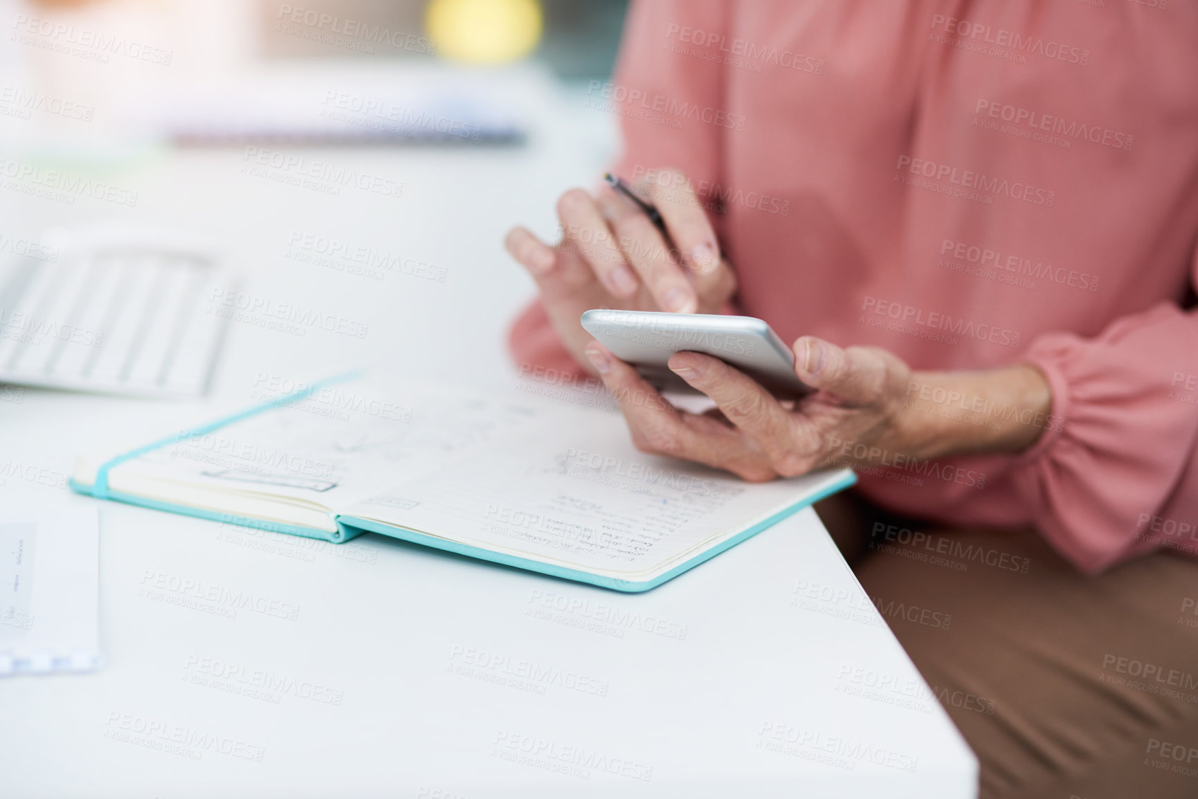 Buy stock photo Shot of an unrecognizable mature woman writing down details from her cellphone to her diary at work