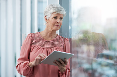 Buy stock photo Shot of a mature businesswoman using her digital tablet at work