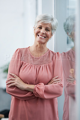 Buy stock photo Portrait of a cheerful mature businesswoman posing with her arms folded in her office at work