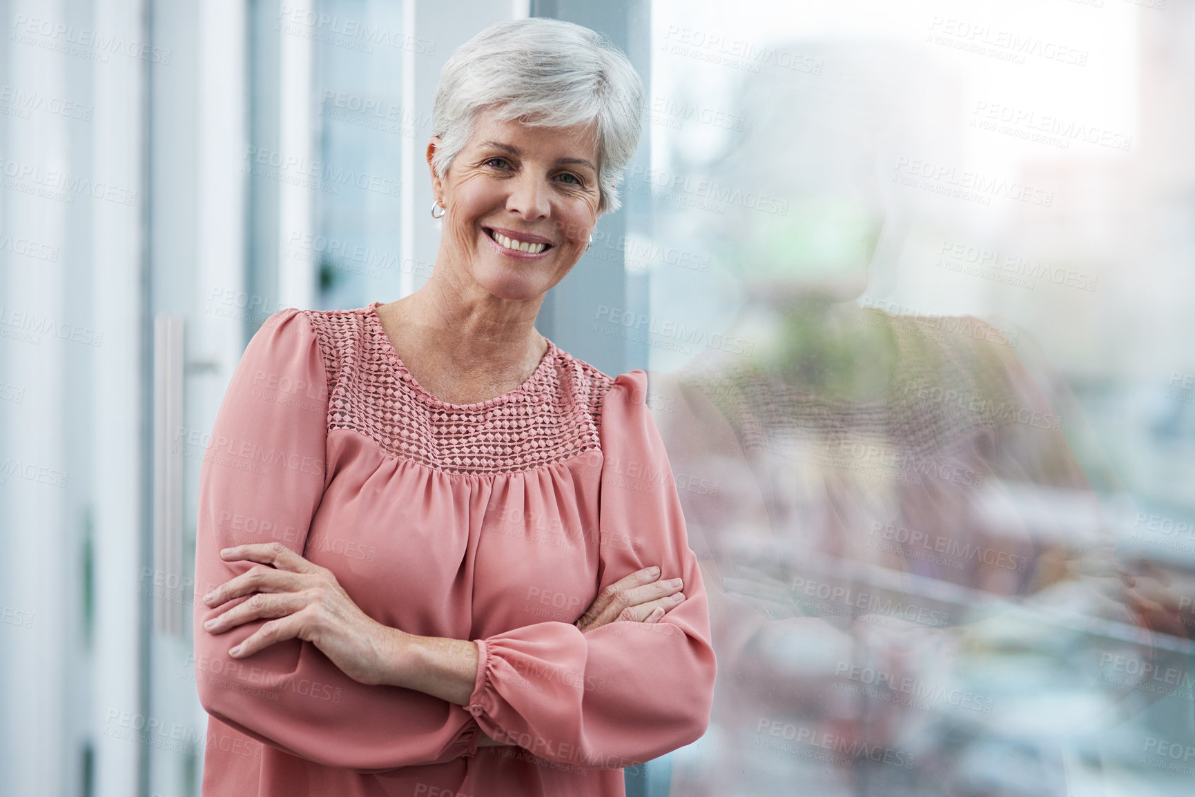 Buy stock photo Portrait of a cheerful mature businesswoman posing with her arms folded in her office at work