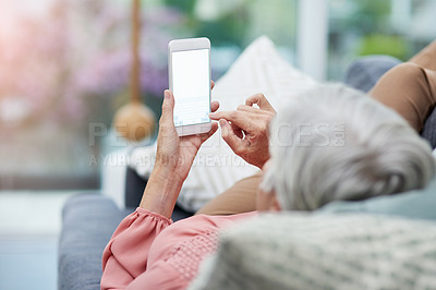 Buy stock photo Rearview shot of a mature woman using her cellphone while relaxing on a sofa at home