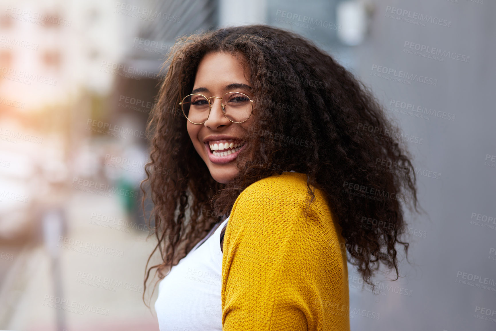 Buy stock photo Cropped portrait of a happy young woman standing outdoors in an urban setting