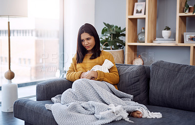 Buy stock photo Full length shot of an attractive young woman suffering from stomach cramps while sitting on a sofa at home