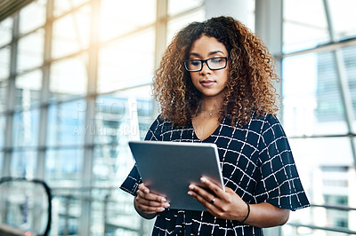 Buy stock photo Cropped shot of an attractive young businesswoman using a digital tablet while standing in a modern office