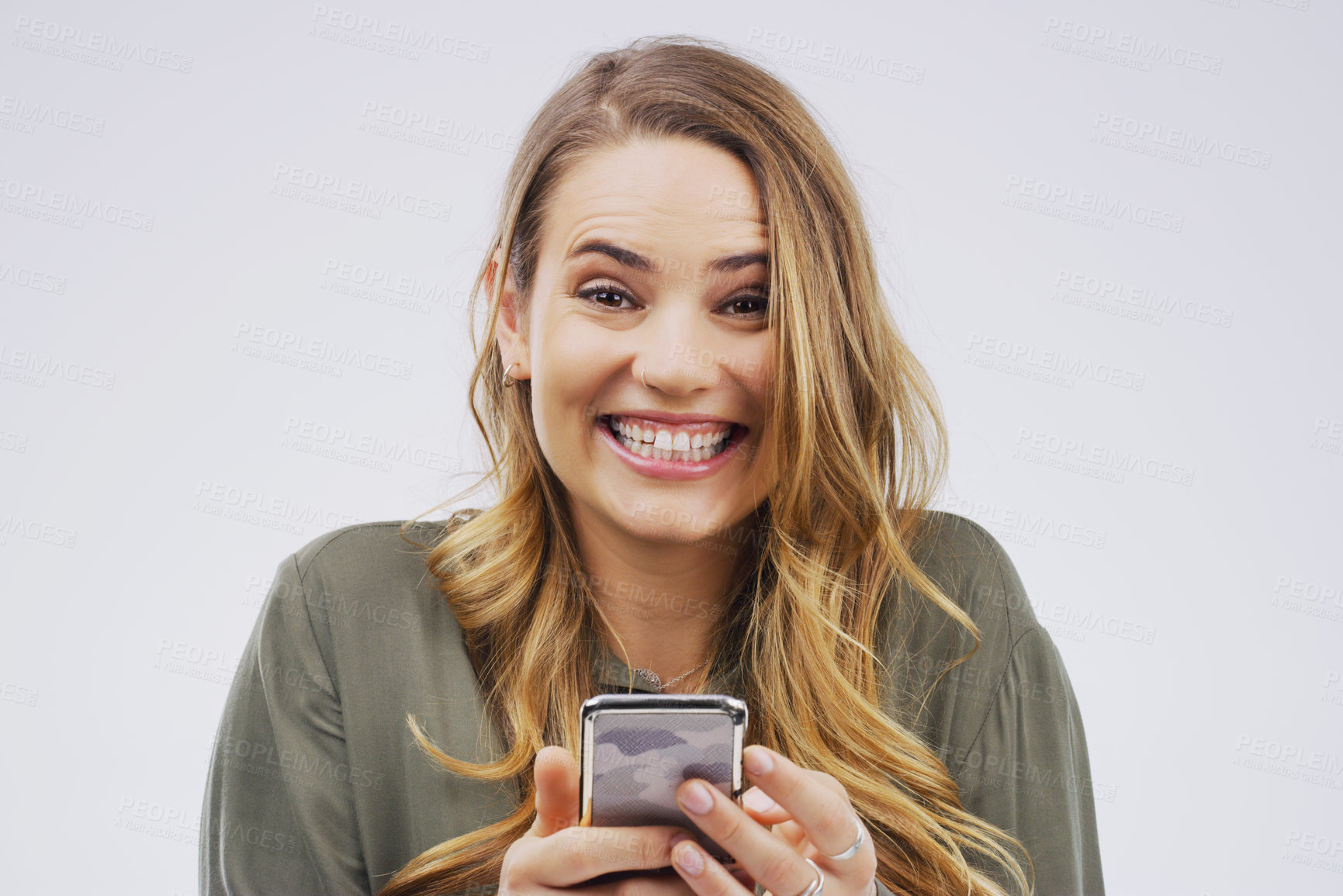 Buy stock photo Studio shot of a young woman looking excited while using her cellphone
