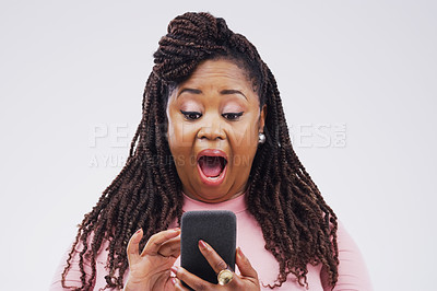 Buy stock photo Studio shot of a young woman looking surprised while reading something on her cellphone