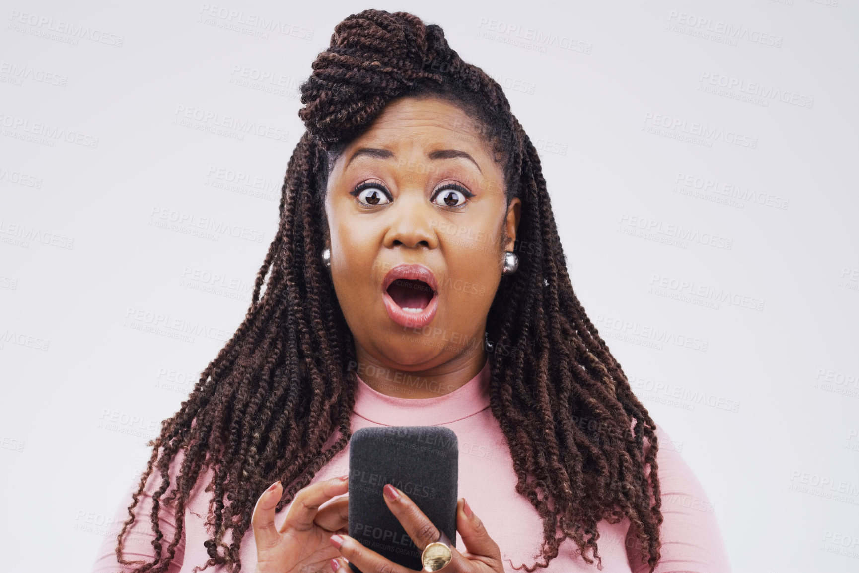 Buy stock photo Studio shot of a young woman looking surprised while reading something on her cellphone