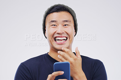 Buy stock photo Comic, portrait and Asian man with a smartphone, funny and happiness against a grey studio background. Face, male person and guy with a cellphone, mobile app and meme with a smile, joy and connection