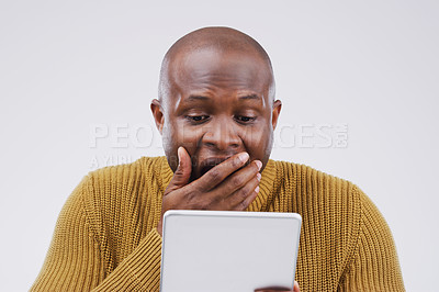 Buy stock photo Studio shot of a young man looking surprised while using a digital tablet