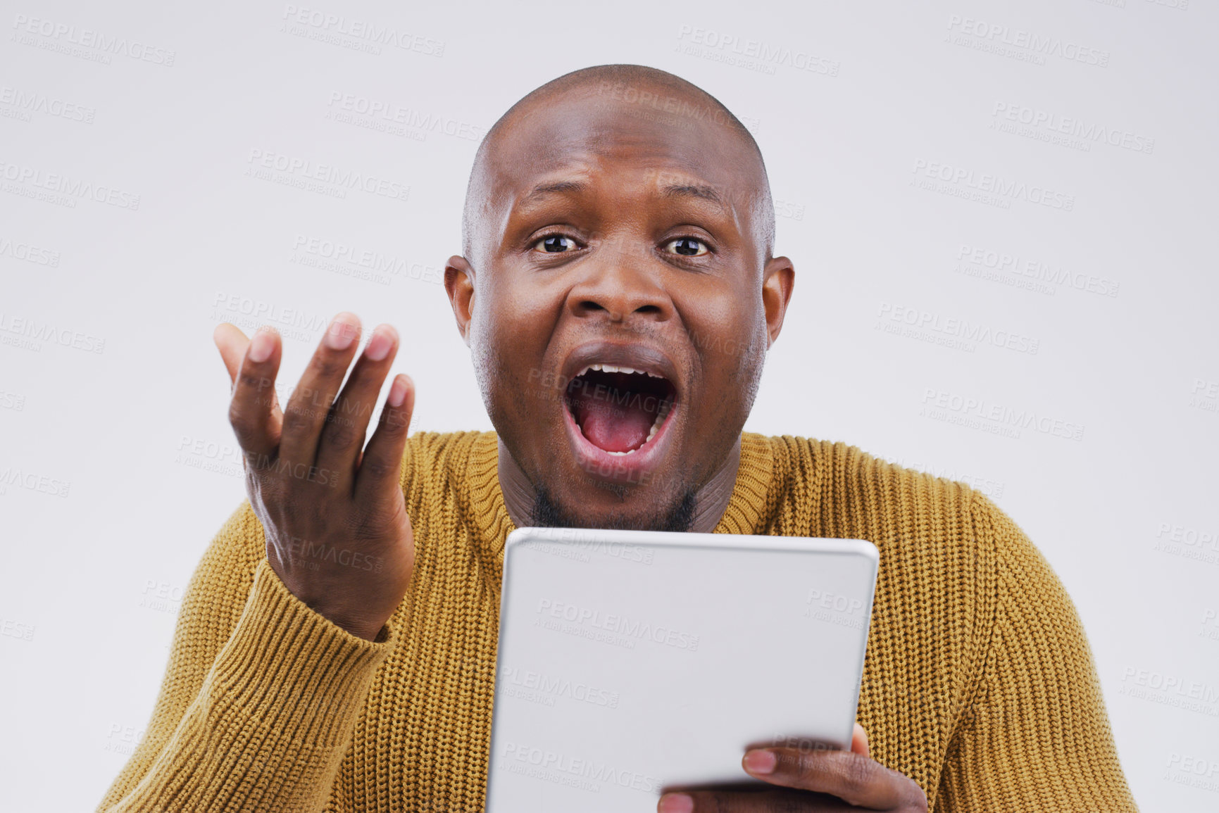Buy stock photo Studio shot of a young man looking surprised while using a digital tablet