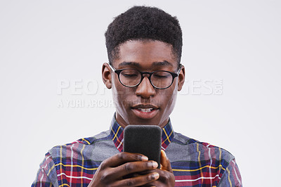 Buy stock photo Studio shot of a handsome man using his cellphone against a grey background