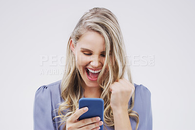 Buy stock photo Studio shot of a woman cheering while reading something on her cellphone