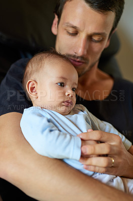 Buy stock photo Shot of an affectionate young father holding and bonding with his infant son at home