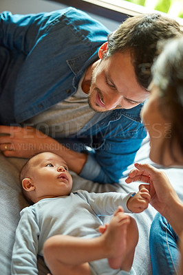 Buy stock photo Shot of a beautiful young couple playing with their infant baby boy at home