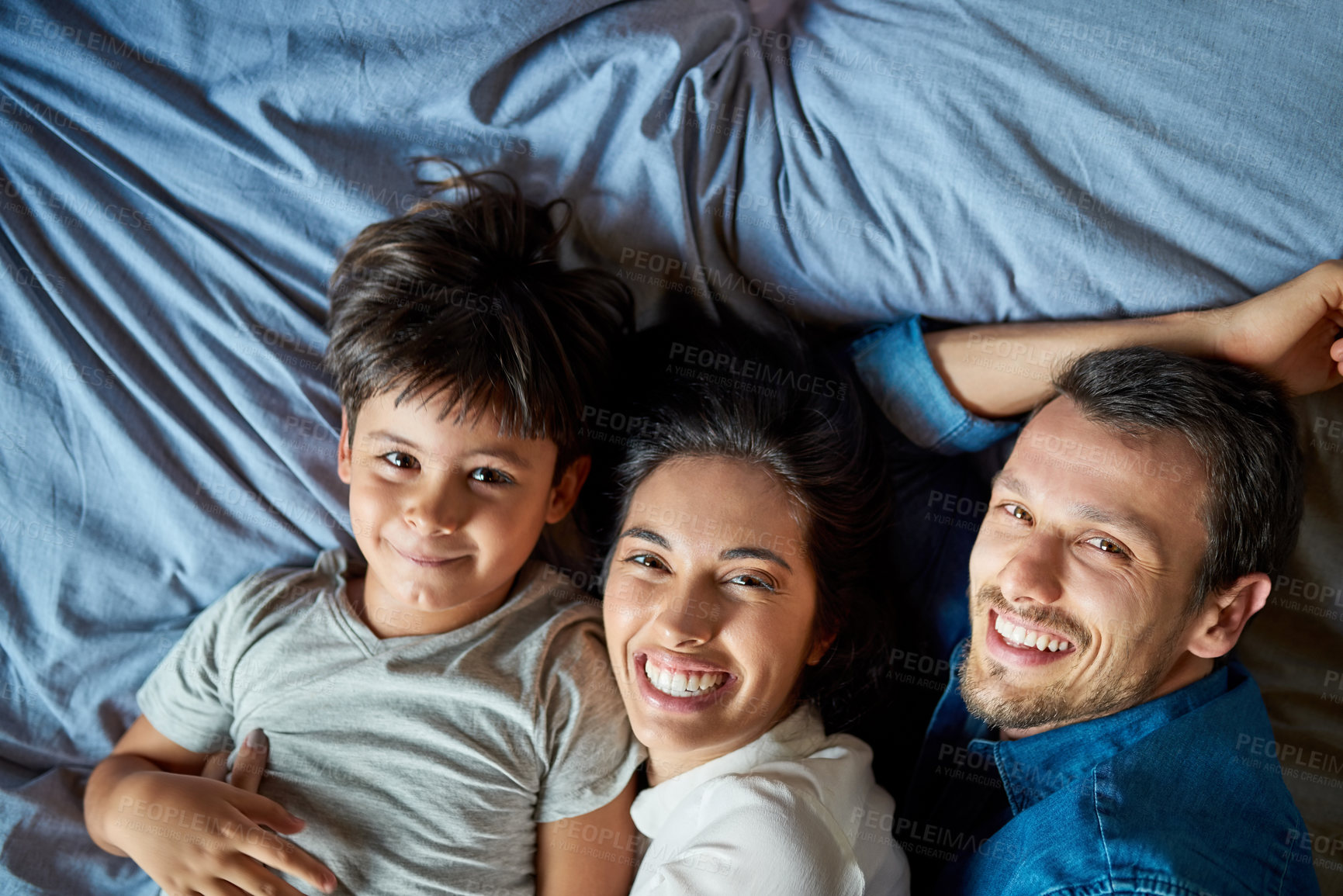 Buy stock photo Portrait of a beautiful young couple and their son laying in bed together at home
