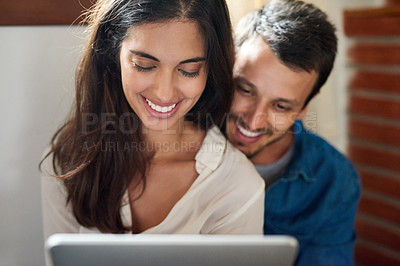 Buy stock photo Shot of an affectionate young couple using a digital tablet together at home