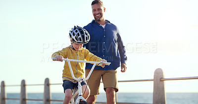 Buy stock photo Shot of a cheerful father teaching his son how to ride a bicycle outdoors