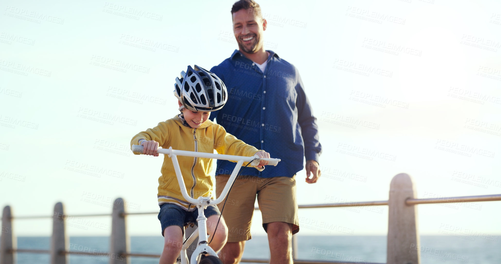 Buy stock photo Shot of a cheerful father teaching his son how to ride a bicycle outdoors