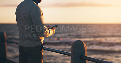 Buy stock photo Man, phone and texting on promenade by ocean with sunset sky on vacation with contact on web. Person, smartphone and outdoor by sea, waves and back on holiday by horizon with app for social media