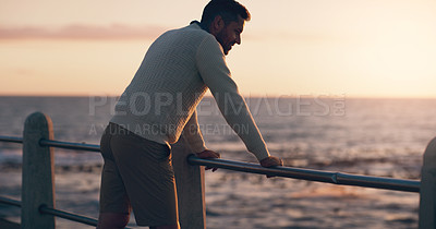 Buy stock photo Rearview shot of a man watching the sun set at the beach