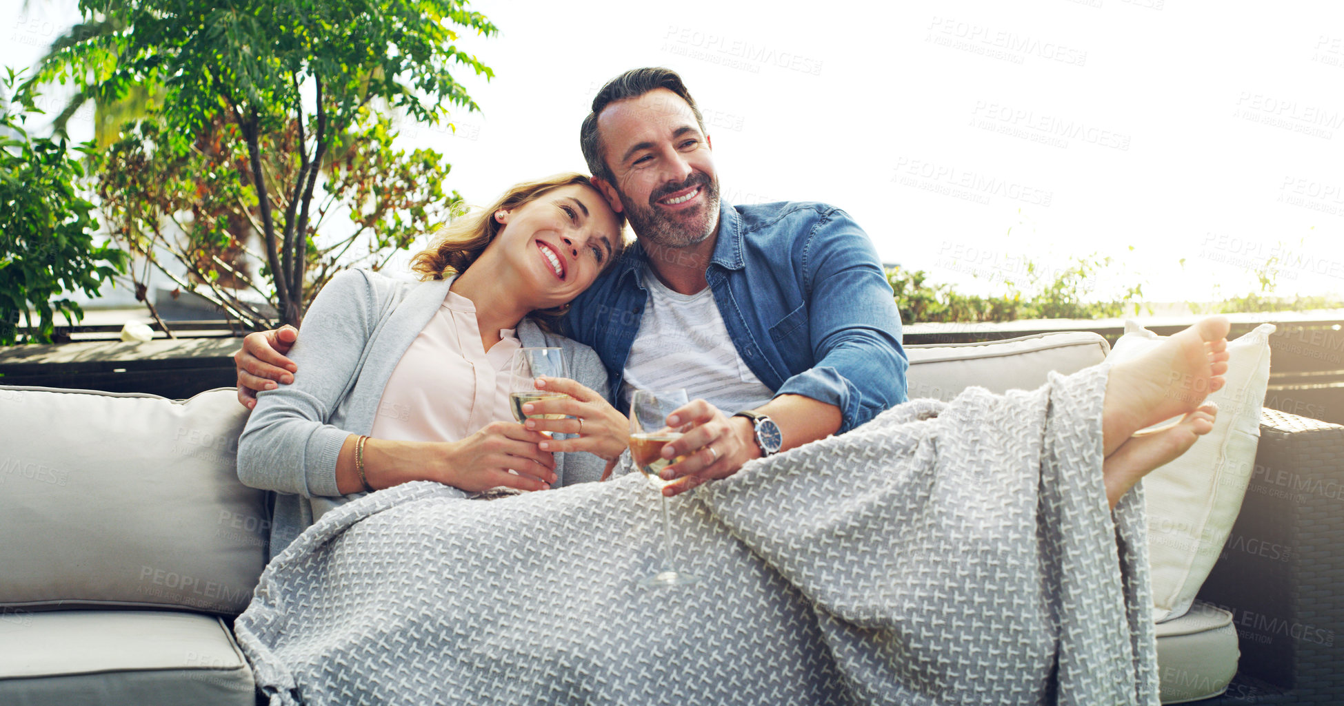Buy stock photo Drinks, relax and couple on hotel terrace with smile, embrace and tropical holiday fun together. Blanket, man and happy woman on outdoor couch with wine, cozy romance and date on calm travel vacation