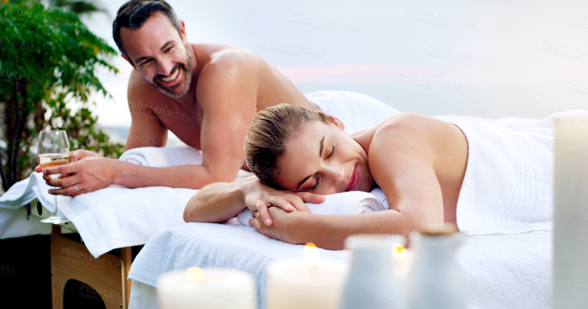 Buy stock photo Love, spa and couple outdoor for massage, vacation and resting on table on a zen balcony. Relax, peace and man with woman at a luxury resort for wellness, treatment or body therapy, candles and wine