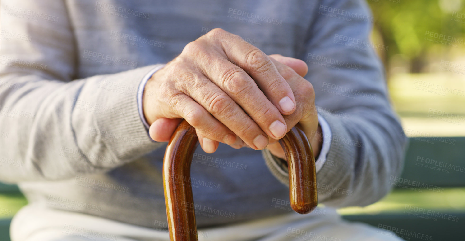 Buy stock photo Closeup of senior hands on a walking cane for help, assistance or healthcare in outdoor park. Nature, retirement home and zoom of elderly male person with disability sitting in garden with wood stick