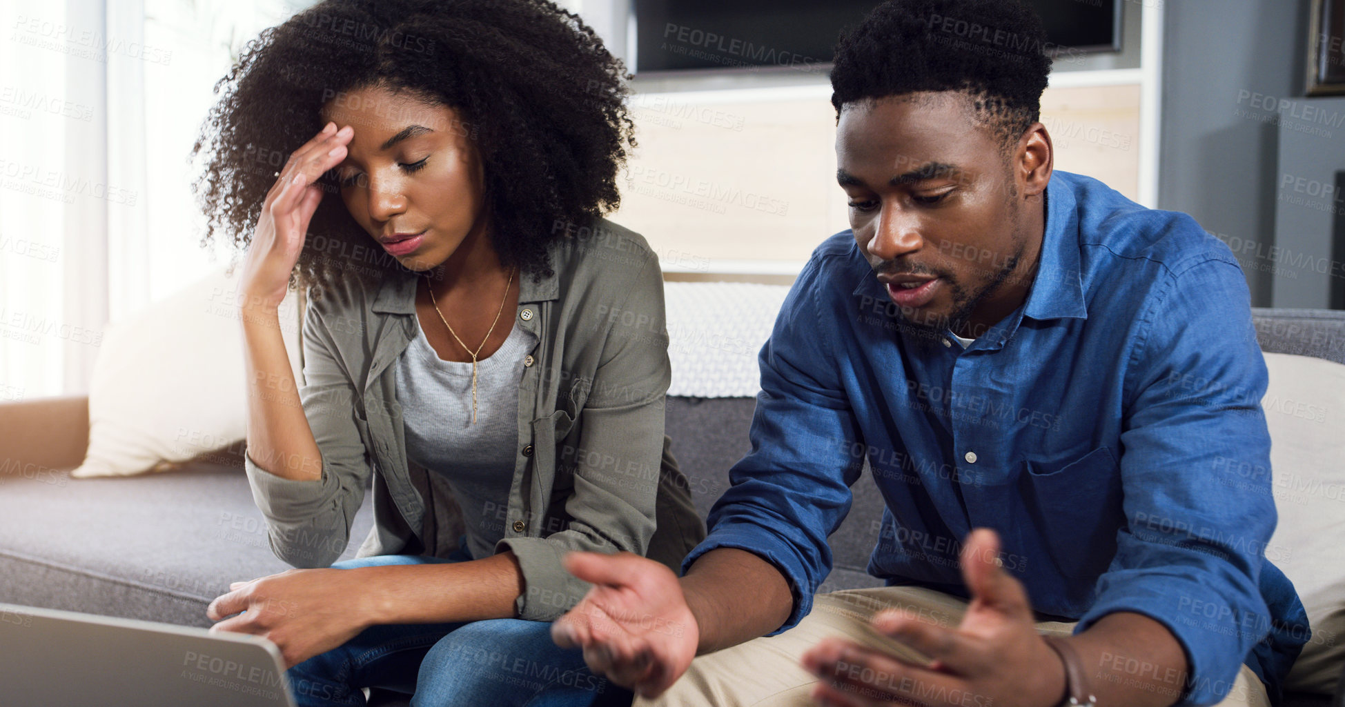 Buy stock photo Shot of a young couple using a laptop together and having an argument in the lounge at home