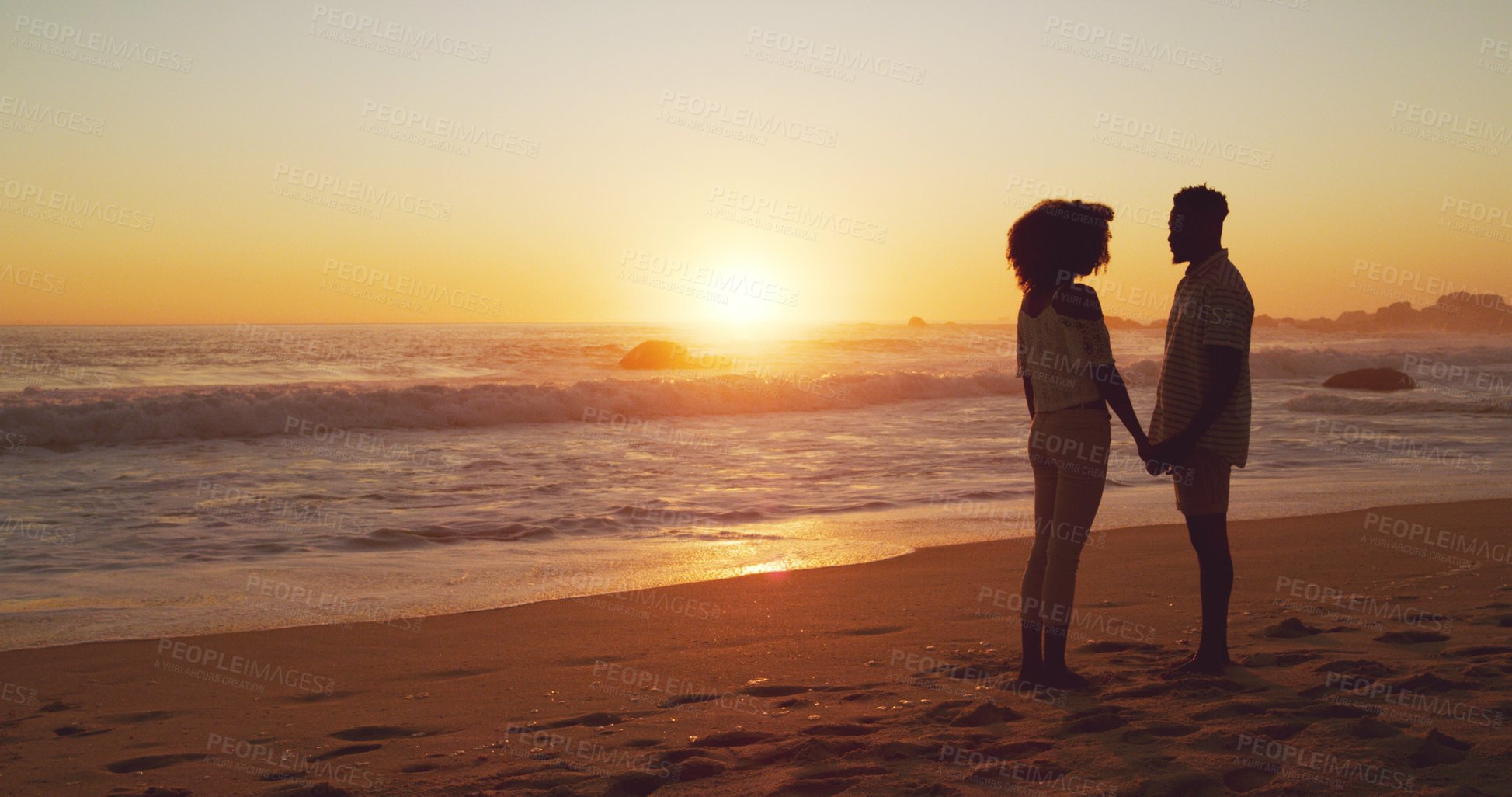 Buy stock photo Full length shot of an affectionate young couple standing on the beach at sunset