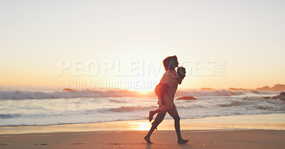 Buy stock photo Full length shot of an affectionate young couple taking a stroll on the beach at sunset