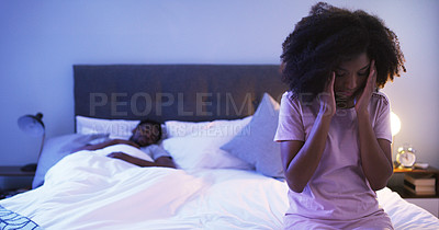 Buy stock photo Shot of a concerned looking young woman sitting on a bed with her husband sleeping in the background